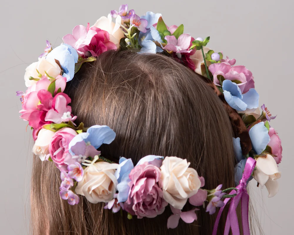 Mākslīgs vainags ar ziediem no rozā paletes.