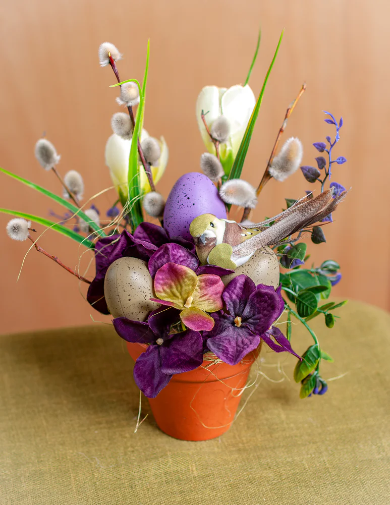 Raibs floristikas kārtojums ar pūpoliem, putniņiem podiņā priekš Lieldienām