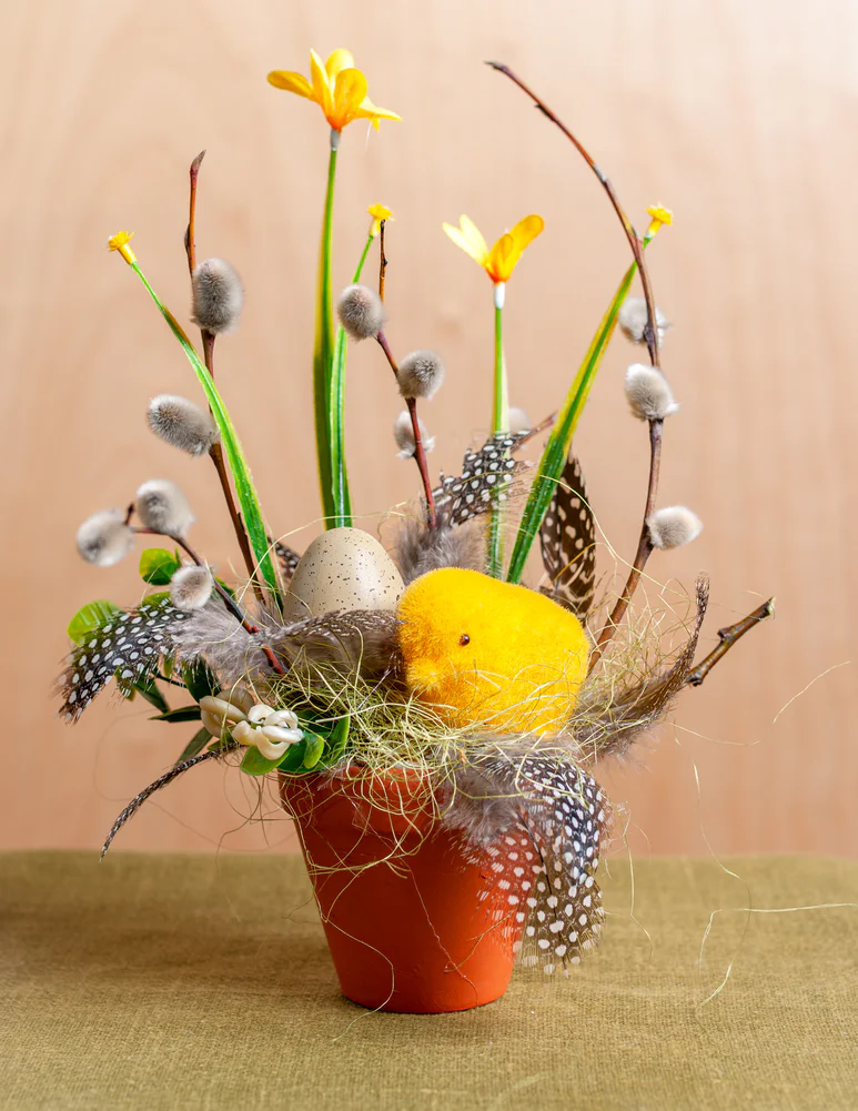Dzeltenīgs floristikas kārtojums ar pūpoliem un zaķi podiņā priekš Lieldienām